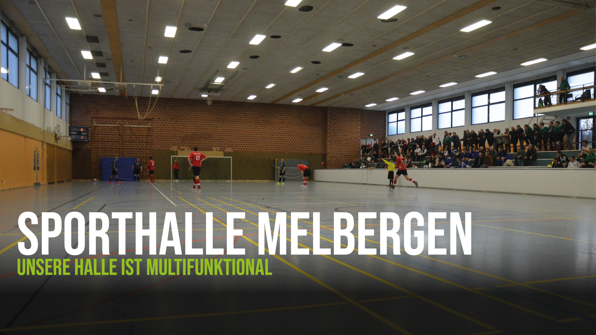 Die Sporthalle Melbergen in Löhne-Gohfeld von innen, respektive mit Blick auf das Spielfeld und im Hintergrund die Tribüne.